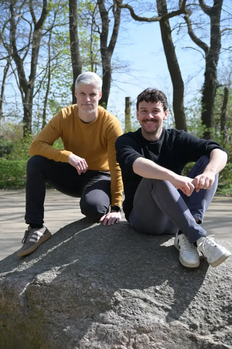 Frederik Wilkening und Oliver Schmidt sitzen im Wald auf einem Felsen